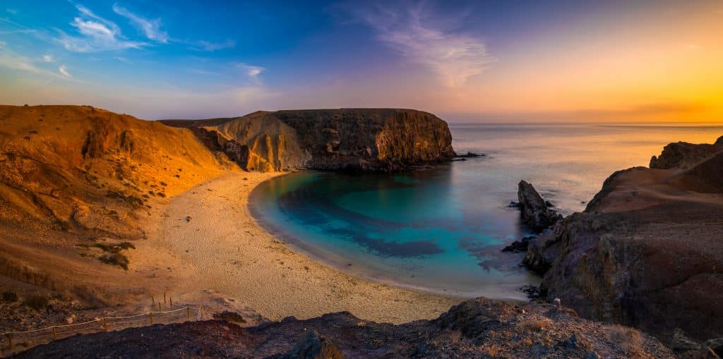 Bucht Playa de Papagayo auf Lanzarote mit türkisblauem Wasser und goldenen Klippen bei Sonnenuntergang